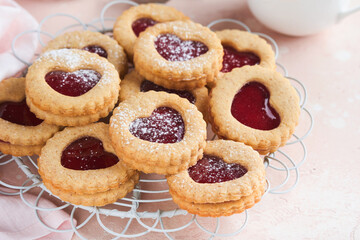 Traditional Linzer cookie with strawberry jam and powder sugar on pink beautiful background. Top view. Traditional homemade Austrian sweet dessert food on Valentines Day. Holiday snack concept.