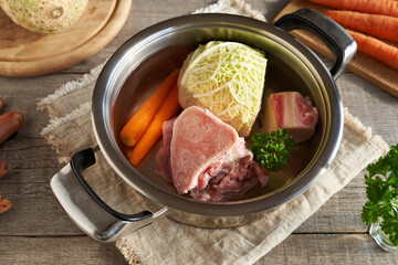 Marrow bones, beef meat and fresh vegetables in a pot - preparation of bone broth - obrazy, fototapety, plakaty