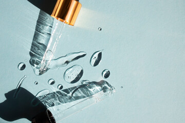 Drops of gel-like cosmetic liquid and glass pipettes on a blue background. Top view, place for text.