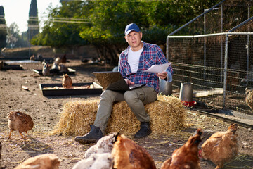 Farmer looking at contract in chiken farm © JENOCHE