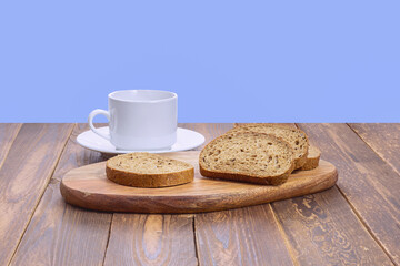 slices of rye bread with seeds and a white mug with a saucer on a wooden board