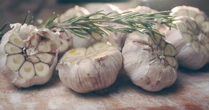 Garlic and a sprig of rosemary on a board in the rays of bright light