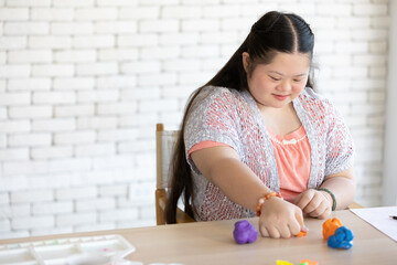 down syndrome girl sculpt plasticine figures on a table