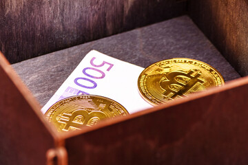 Bitcoins and euro banknote in a wooden box. Forgotten purchase. Successful investment.