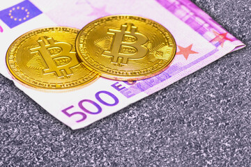 Bitcoin and euro banknote on the gray asphalt.