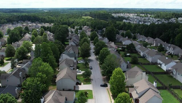 Pull away drone aerial view over an American lush green suburban neighborhood.
