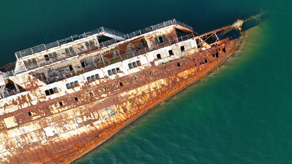 Aerial drone top down photo passenger rusty ship wreck half sunk near shore