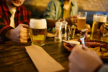 Close-up of men drink beer and eat in a pub.