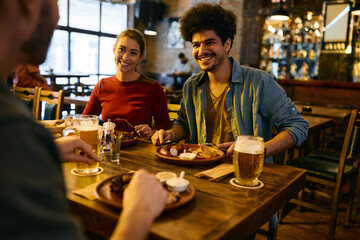 Happy Lebanese man and his Caucasian girlfriend eat lunch with friends in pub.
