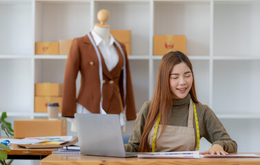 A beautiful Asian woman who owns a clothing brand, she is checking the printed designs, she designs...