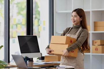 Naklejka premium Woman owner of a startup company selling products online on an online store platform, sending goods through a courier company, Business planning. Online selling and online shopping concepts.