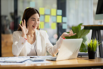 Beautiful Asian woman, she is a call center employee of an Internet and telephone company, she is responsible for providing service and assistance to customers through the phone. Call center concept.