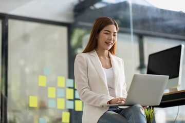 Beautiful Asian young woman looking at information on a laptop, concept image of Asian business woman working smart, modern female executive, startup business woman, business leader woman.