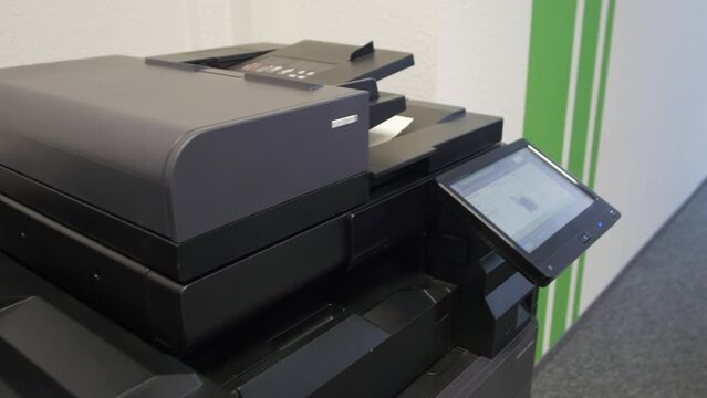 Young man copies documents on a copying system in office