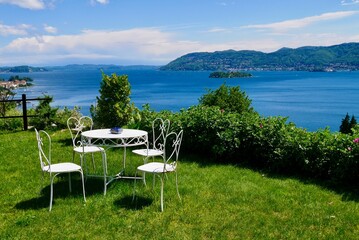 White vintage iron table on a hill above Verbania overlooking Lake Maggiore and the Barromean islands. Piedmont, Italy.
