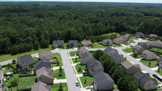 Pull away drone aerial view over an American lush green suburban neighborhood.