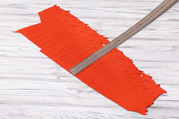 orange dyed genuine natural alligator leather with ruler on the wooden table	