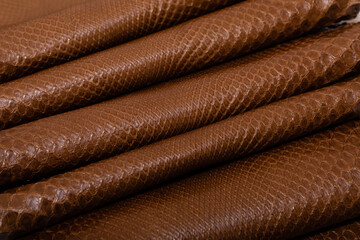 brown dyed folded natural genuine python leather on the wooden table	