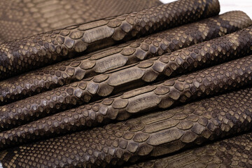 brown khaki dyed folded natural genuine python leather on the wooden table	
