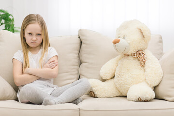 Photo of little girl looking sadly at the camera with teddy bear. © Andrii