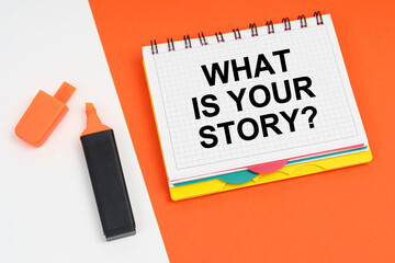 On a white-orange surface lies a marker and a notepad with the inscription - WHAT IS YOUR STORY