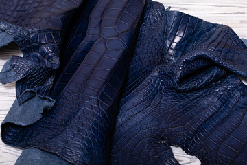 dark blue dyed genuine natural alligator leather on the wooden table	