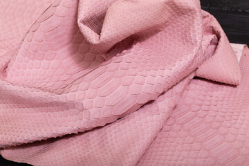 pink dyed genuine natural python leather on the wooden table	
