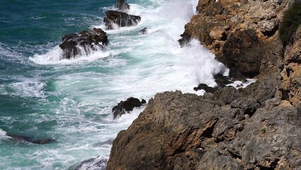 Crystal clear turquoise water, waves crashing on the rocky shore, and the ruins