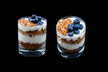 Homemade baked granola with yogurt and blueberries in a glass on a black background. Space for text or design.