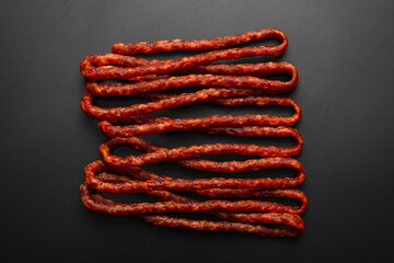 Cabanossi, dry sausage isolated on black background.