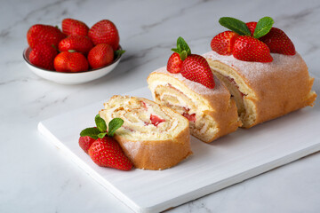 Sweet roll stuffed with strawberry and cream decorated with strawberries, powdered sugar and mint leaves
