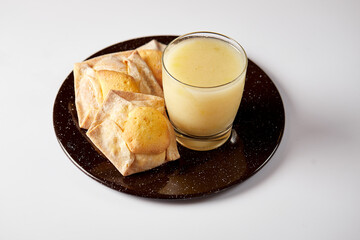 Homemade ecuadorian quesadilla accompanied by rosero, a traditional drink made of mote, fruit and rose petals. It’s served on a black plate with a white background