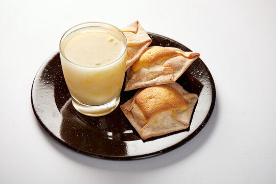 Homemade ecuadorian quesadilla accompanied by rosero, a traditional drink made of mote, fruit and rose petals. It’s served on a black plate with a white background