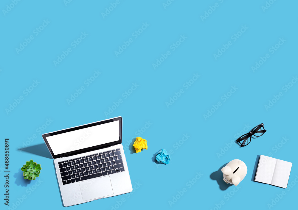 Poster laptop computer with a piggy bank and office objects - flat lay
