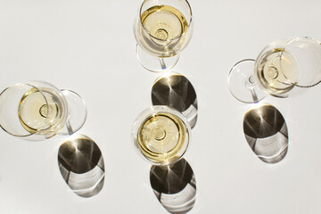 White wines into glass on white table with black shadow above view	