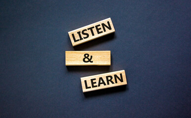Listen and learn symbol. Concept words Listen and learn on wooden blocks. Beautiful black table...