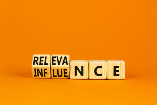 Influence or relevance symbol. Turned wooden cubes and changed the word Influence to Relevance. Beautiful orange table orange background. Business influence or relevance concept. Copy space.
