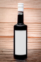 bottle with black drink and blank white label on wooden background.copy space