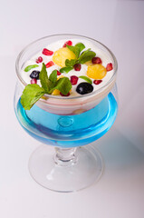 Cup with a dessert of milk, garnished with mint, pomegranate and pineapple.