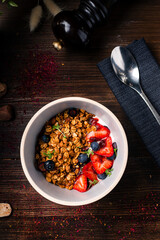 Healthy breakfast ingredients. Bowl of oat granola with fresh berries and honey. Top view