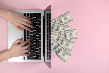 Fototapeta na wymiar Laptop keyboard and dollar bills. Female hands typing on wireless keyboard, flat lay workspace. Freelance concept, pink background, top view and copy space photo