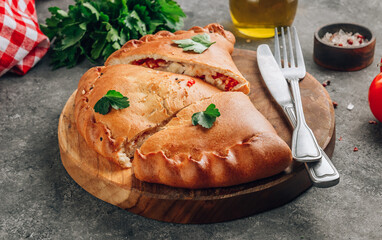Italian food, closed pizza calzone with cheese, gray stone background.