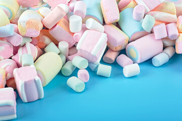 Colorful marshmallows on a blue background. Delicious dessert. Fluffy marshmallows.
