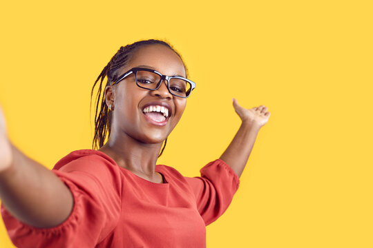 Happy Cheerful Confident Black Woman Takes Selfie, Films Tourist Sightseeing View Travel Vlog Or New Home Room Tour, Shares Positive Emotions, Inviting Welcoming Gesture On Empty Blank Mockup Backdrop