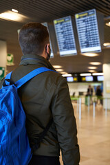 Young man with backpack in airport looking flight timetable