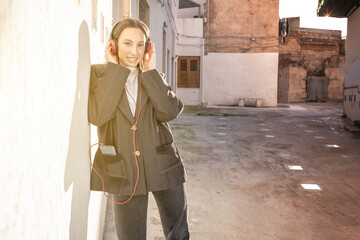 Smiling young girl in trendy jacket using earphones
