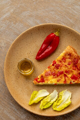 Piece of chickpea flour kalinte dish with pickled fermented red pepper and olive oil.