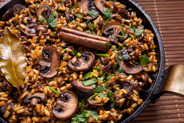 Mushroom pilau dish with rice and champignon fungi on sauce pan with spices. Vegan cuisine.