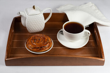 a cup of tea with a bun and a white napkin on a tray