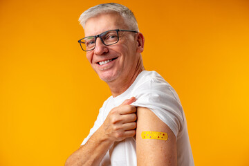 Senior man against yellow background recieved corona virus vaccination - Powered by Adobe